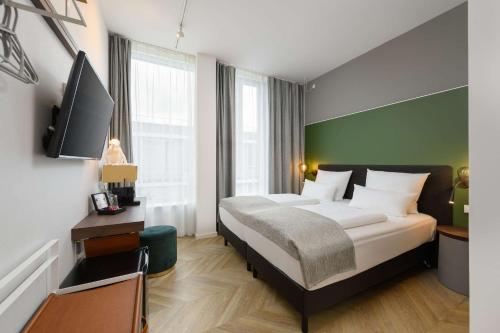 a bedroom with a bed and a flat screen tv at Flightgate Munich Airport Hotel, a member of Radisson Individuals in Hallbergmoos