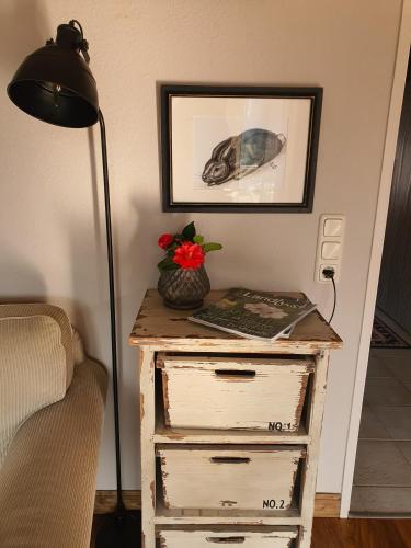 a table with a lamp and a dresser with a flower on it at PIER19Farmhouse in Emden