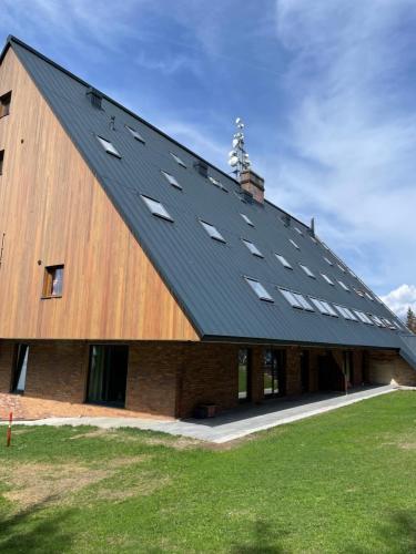 a large barn with a black roof with windows at Apartmán Žalý in Benecko