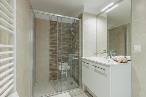 une salle de bain blanche avec un lavabo et une douche dans l'établissement Résidence Senior Marina Bay, à Villeneuve-Loubet