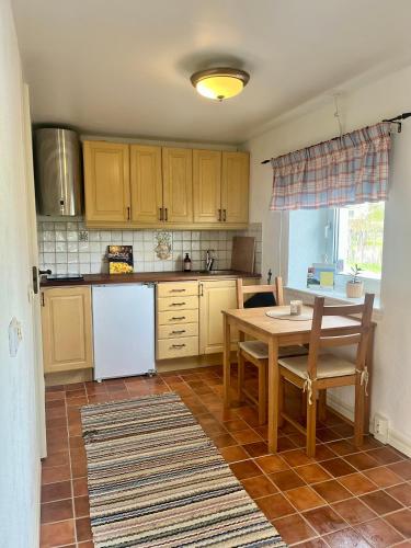 a kitchen with a table and a white refrigerator at Lantlig lägenhet nära stranden in Lilla Beddinge