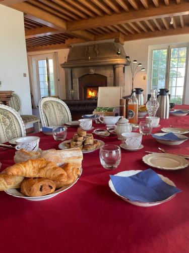 a table with bread and wine glasses and a fireplace at Château Philip in Saint-Genest-Lerpt