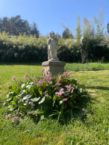 a statue in a garden with flowers in the grass at Château Philip in Saint-Genest-Lerpt