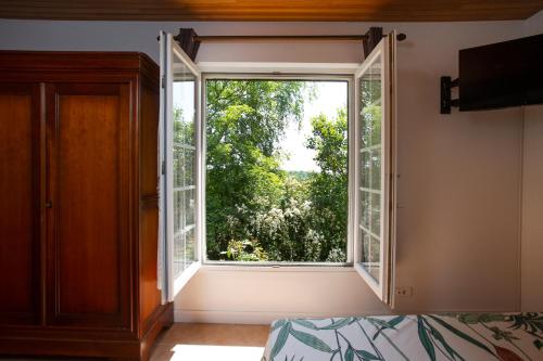 an open window in a room with a bed at La Mancellière de Montjoie chambres d'hôtes et gîtes in Saint-Michel-de-Montjoie