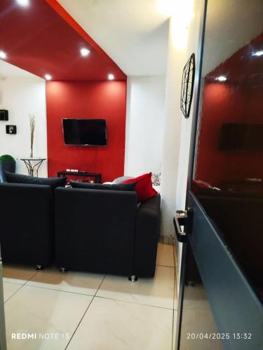 a living room with a black couch and a red wall at Ecrin de douceur chic en ville in Lomé