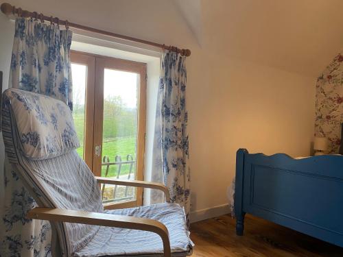 a room with a rocking chair and a window at Gîte des Pommiers avec terrain de pétanque in Le Fresne-Poret