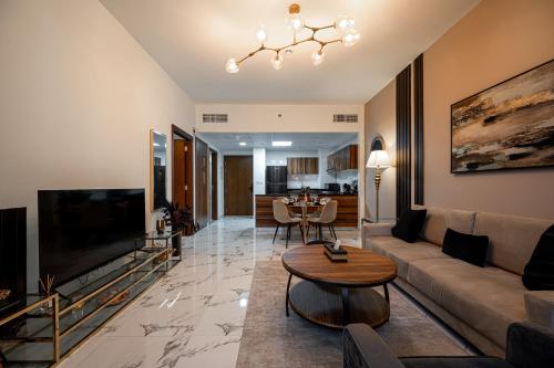 a living room with a couch and a tv and a table at Fabulous Brand New 1BR, Gym Pool & Balcony in Ras al Khaimah