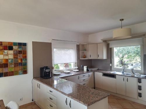 a kitchen with white cabinets and a large window at Villa Panoramic Paradise in São Brás de Alportel