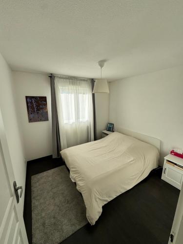 une petite chambre avec un lit blanc et une fenêtre dans l'établissement Charming apartment near Geneva, à Saint-Julien-en-Genevois