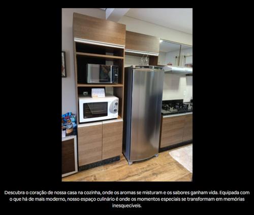 a kitchen with a stainless steel refrigerator and a microwave at Residencial Luce Del Sole - Apto Nº 2 in Joinville