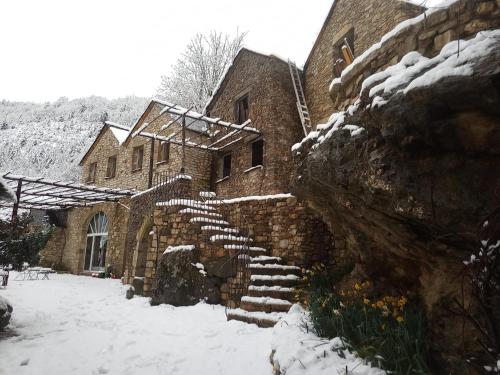 a stone building with snow on the steps at La ferme des Cévennes in Florac Trois Riviere
