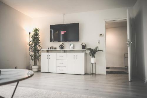 a living room with a white cabinet and a flat screen tv at Maisonette Apartment mit Panorama Terrasse in Kaiserslautern WeHome Premium in Kaiserslautern