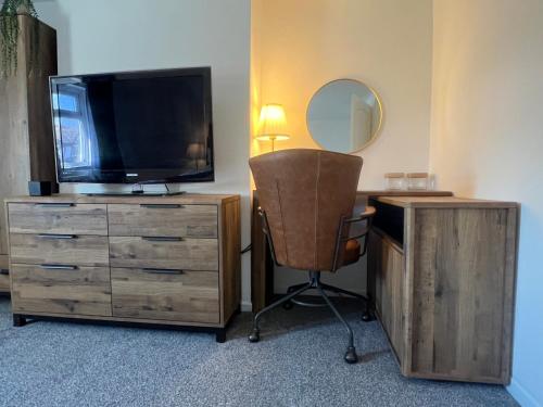 a room with a desk with a television and a chair at Comfy and Connected Standish Home - Two Mins from M6 Jct-27 in Standish