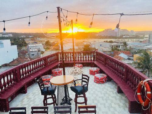 einen Balkon mit einem Tisch und Stühlen sowie Blick auf den Sonnenuntergang in der Unterkunft Kaze Home Nhon Ly in Quy Nhon