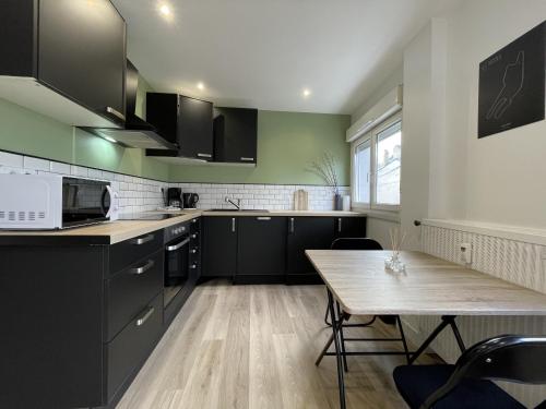 une cuisine avec des armoires noires et une table en bois dans l'établissement Le Scudéria - Centre - 3p - Rêve au Mans, au Mans