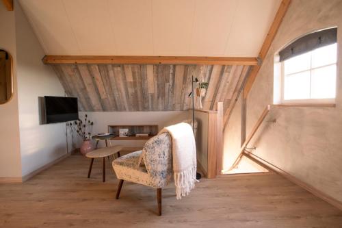 a attic room with a chair and a table at B&B Country Suite Den Oord in Terwolde