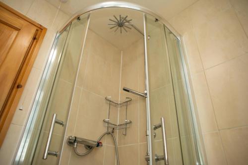 a bathroom with a shower with a clock on the wall at Orchid Cottage Aberporth in Aberporth
