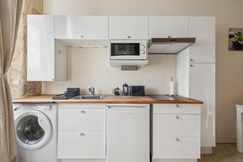 une cuisine blanche avec une machine à laver et un micro-ondes dans l'établissement BnBNova - Ile St Louis, à Paris