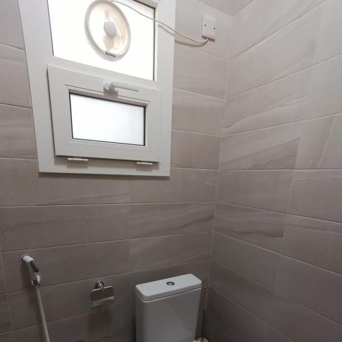 a bathroom with a white toilet and a window at Darunique Inn in Nizwa