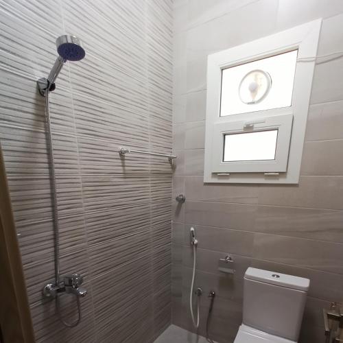 a bathroom with a shower and a toilet with a window at Darunique Inn in Nizwa
