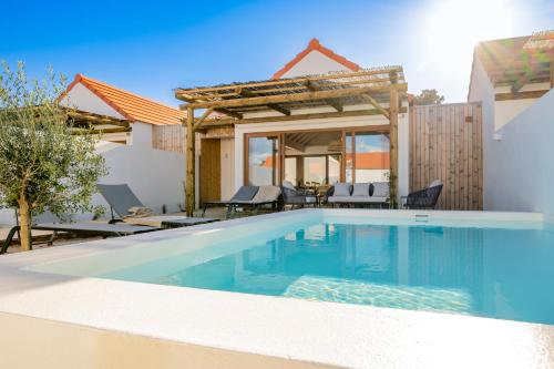 a swimming pool in front of a villa at Pestana Comporta Village Residences in Comporta