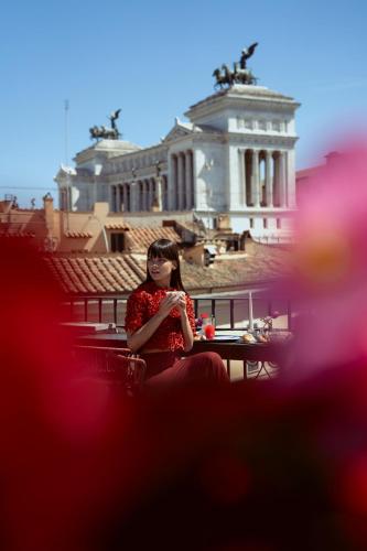 a woman sitting at a table in front of a building at Otivm Hotel in Rome