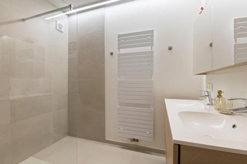 a white bathroom with a sink and a shower at Evasion mer à Ostende in Ostend