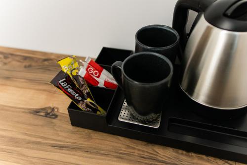 a black coffee maker with two cups and candy at TisArt Hotel in Tismana