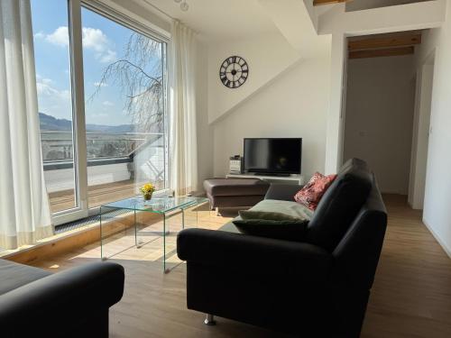 Una sala de estar con un sofá y una ventana grande. en Ruhrtalblick Apartments - Auszeit mit Ausblick, en Meschede
