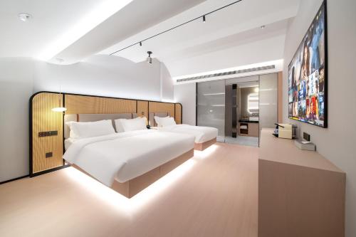a bedroom with a large white bed and a tv at Liuxiang Shangcui Hotel in Suzhou