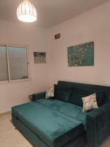 a living room with a green couch and a window at Farah sfax in Sakiet ez Zit