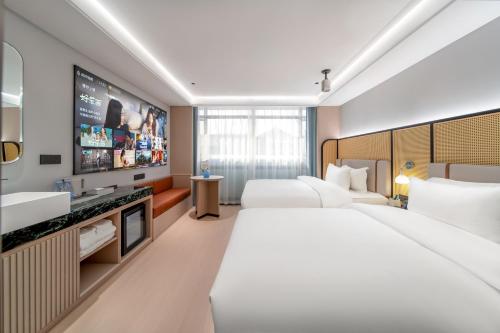 a hotel room with two beds and a flat screen tv at Liuxiang Shangcui Hotel in Suzhou