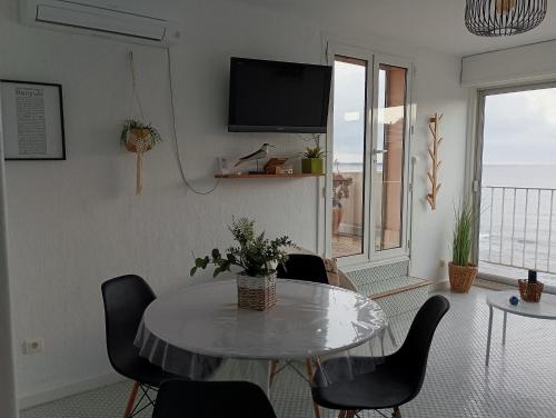 un salon avec une table, des chaises et une télévision dans l'établissement Le Rooftop Des Elmes, T2 Vue mer, à Banyuls-sur-Mer