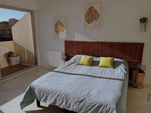 - une chambre avec un grand lit et 2 oreillers jaunes dans l'établissement Le Rooftop Des Elmes, T2 Vue mer, à Banyuls-sur-Mer
