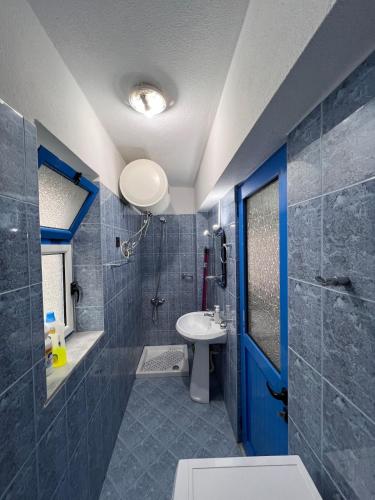 une salle de bain avec une porte bleue et un lavabo dans l'établissement CozyVibe, à Saranda