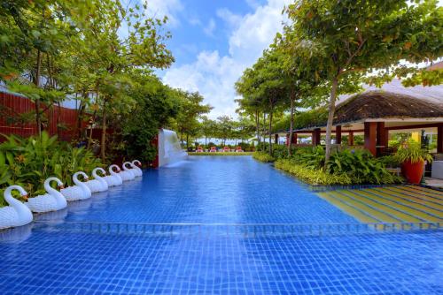 a pool at a resort with trees and a building at Mayfair Waves in Puri