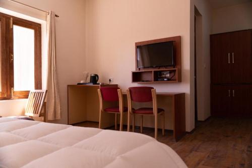 a hotel room with a bed and a desk with two chairs at Hotel Ladakh Delight in Leh