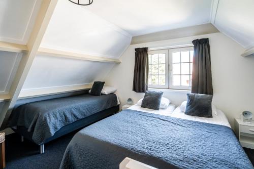 a bedroom with two beds and a window at Duinhotel Haga in Zoutelande