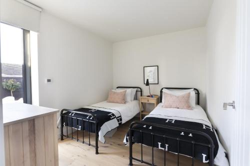 twee bedden in een kamer met witte muren bij Tide's Watch in Beadnell