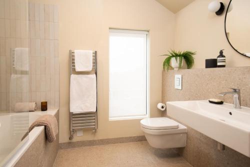 een badkamer met een wastafel, een toilet en een raam bij Tide's Watch in Beadnell