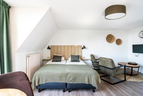 a bedroom with a bed and two chairs at Duinhotel Haga in Zoutelande