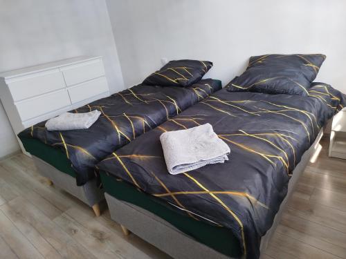 a bed with a black comforter and two pillows at Słoneczny Apartament in Gniezno