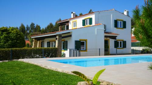 a villa with a swimming pool in front of a house at Zéfiro Ericeira in Ericeira