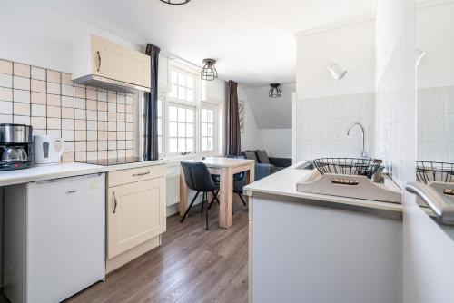 a kitchen with white appliances and a table at Duinhotel Haga in Zoutelande