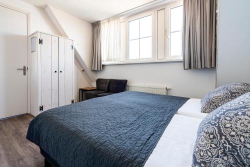 a bedroom with a bed and a chair and windows at Duinhotel Haga in Zoutelande
