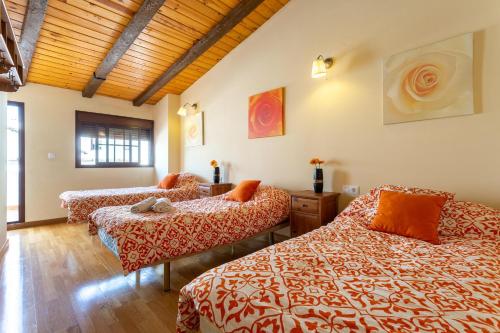 a bedroom with three beds and a wooden ceiling at Alojamiento Rural Benaocaz in Benaocaz