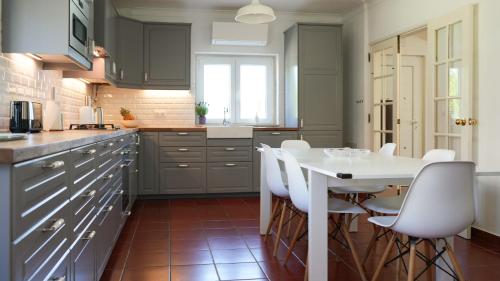 a kitchen with a white table and white chairs at Zéfiro Ericeira in Ericeira