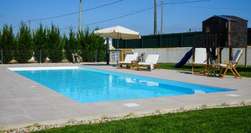 a swimming pool with two chairs and an umbrella at Zéfiro Ericeira in Ericeira