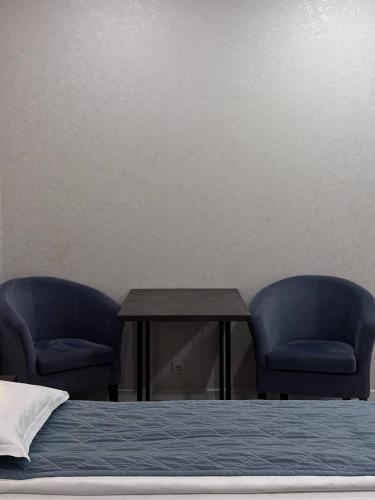two blue chairs and a table and a bed at JETISY COMPLEX in Taraz