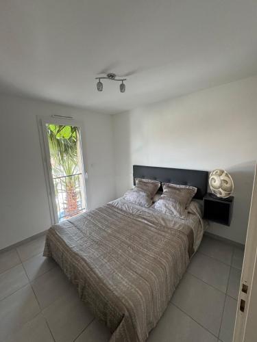 une chambre avec un grand lit dans une pièce blanche dans l'établissement Villa bord de mer Vias plage, à Vias